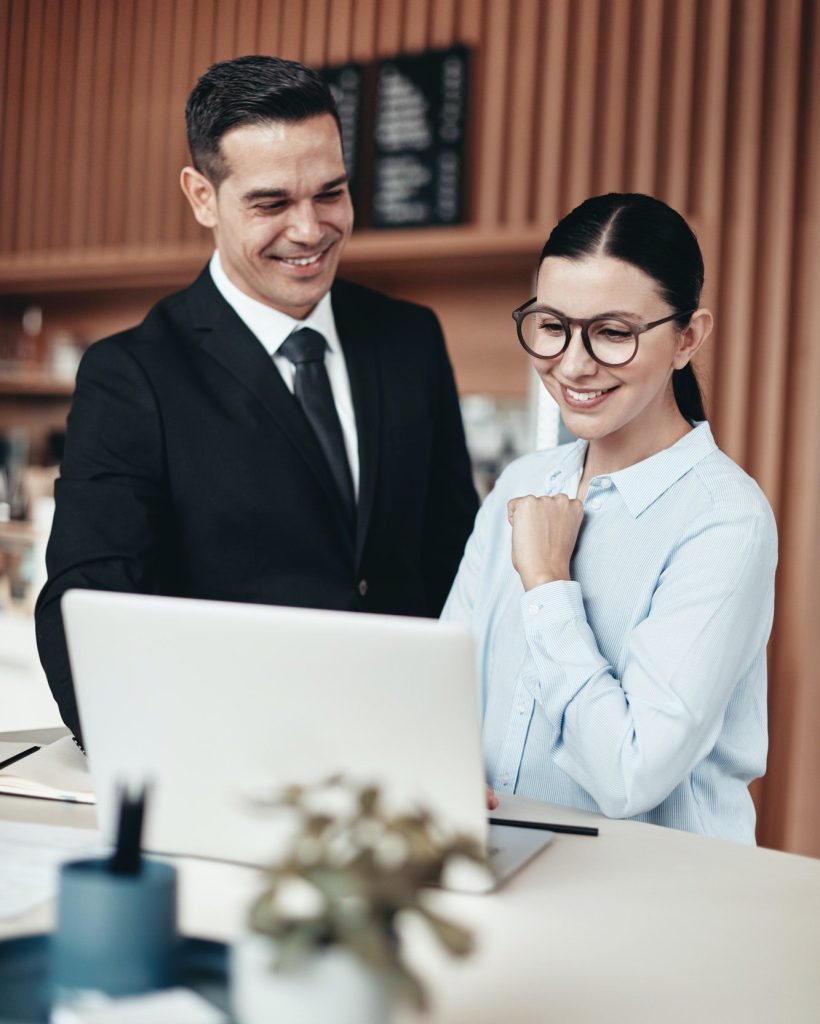 two-smiling-businesspeople-using-a-laptop-together-in-an-office.jpg